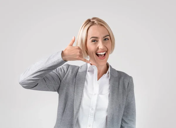 Ritratto di donna d'affari caucasica positiva che mostra il gesto della telefonata su sfondo grigio chiaro dello studio — Foto Stock