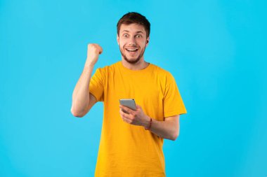 Stüdyoda cep telefonu kullanan heyecanlı adam, online galibiyeti kutluyor