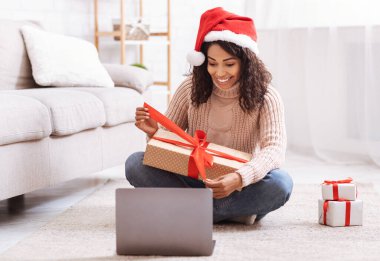 Siyah kadın hediye kutusunu açıyor ve dizüstü bilgisayar kullanılıyor