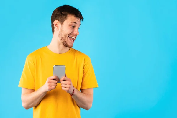 Cara curioso usando telefone celular no estúdio — Fotografia de Stock