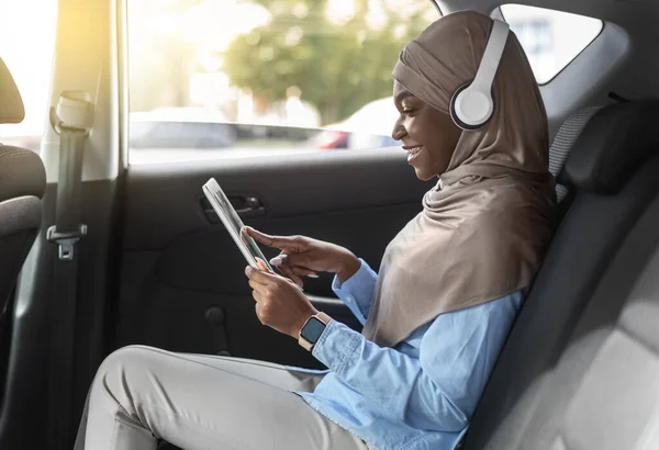 En Car Entertainment. Mujer musulmana negra usando tableta digital mientras monta automóvil —  Fotos de Stock