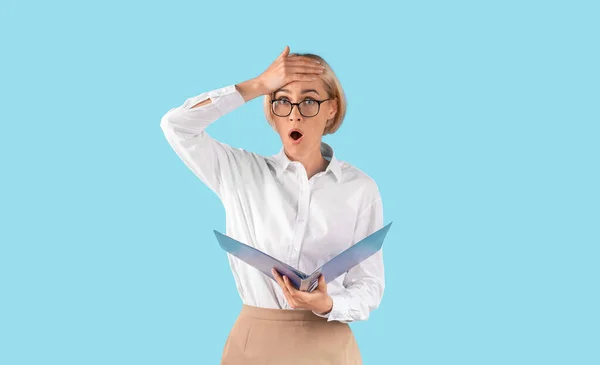 Stresový kancelářský pracovník s dokumenty, šokován omylem, zmeškání termínu, pocit přepracování na modrém pozadí — Stock fotografie