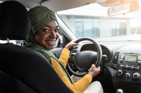 Auto 's kopen. Glimlachende zwarte moslim dame in hidjab testen van nieuwe auto — Stockfoto
