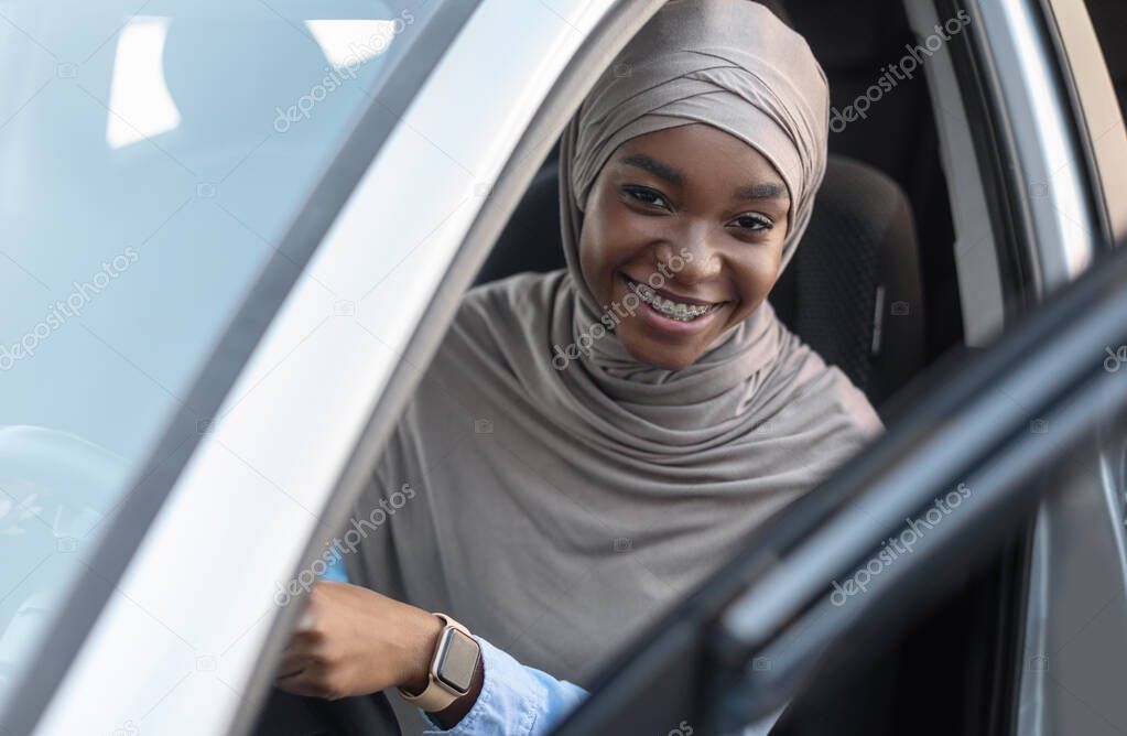 Cheerful Black Muslim Lady Sitting In Her New Automobile, Looking To Camera