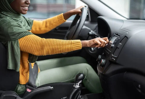 인식 할 수없는 검은 사투리를 가진 여성, 자동차 오디오 시스템의 음량을 조절하는 모습 — 스톡 사진