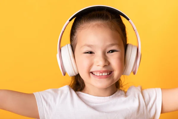 Sorridente ragazza asiatica godendo di musica utilizzando auricolare — Foto Stock