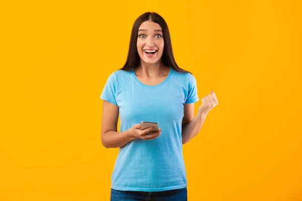 Surprised excited woman using mobile phone at studio — Stock Photo, Image