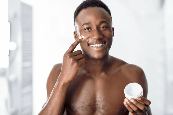 浴室の屋内に立つ顔にクリームを適用する黒人男性 — ストック写真