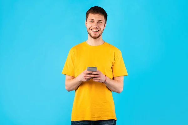 Happy guy met behulp van zijn mobiele telefoon in de studio — Stockfoto