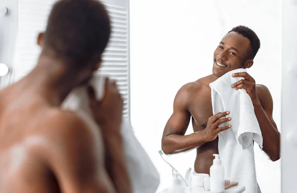 Hombre afroamericano guapo limpiando la cara con toalla en el baño — Foto de Stock
