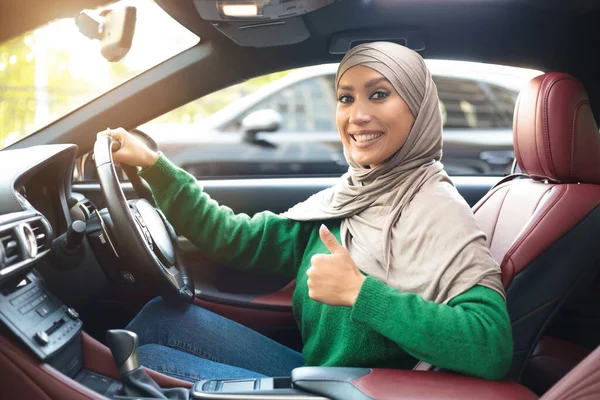 Vrolijke moslim vrouwelijke rijdende auto, met duimen omhoog — Stockfoto