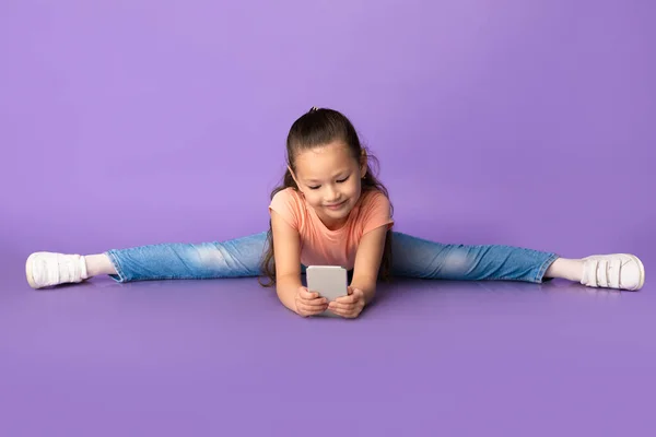 Carino bambina che fa le spaccature e utilizzando smartphone — Foto Stock