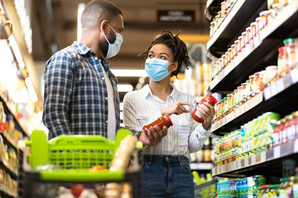 Black Family Couple In Masks Buying Groceries In Supermarket Indoors