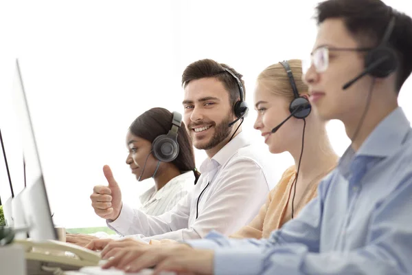 Happy male call centre operator showing thumb up gesture, working with his colleages at modern office — Stock Photo, Image