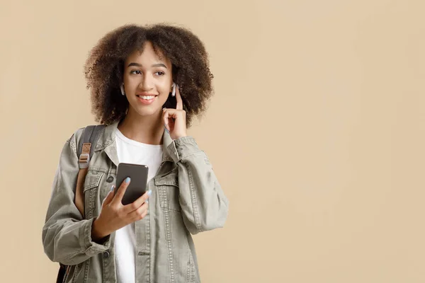 Favoritmusik för en modern promenad. Glad ung snygg afrikansk amerikansk kvinna håller smartphone — Stockfoto