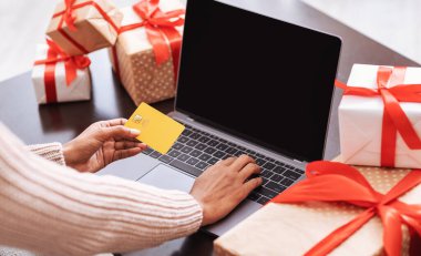 Evde bilgisayar ve kredi kartı kullanan siyah bir kadın.