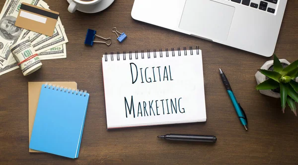 Posa piatta di laptop, soldi e notebook con parole DIGITAL MARKETING sul tavolo dell'ufficio — Foto Stock