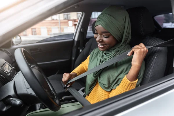 Seguridad del vehículo. Joven negra musulmana dama en hiyab sujeción cinturón de seguridad en el coche — Foto de Stock