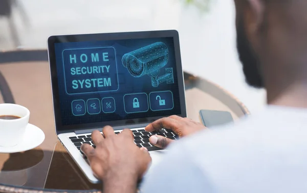 Mand, der bruger sin bærbare computer med hjem sikkerhed ansøgning - Stock-foto