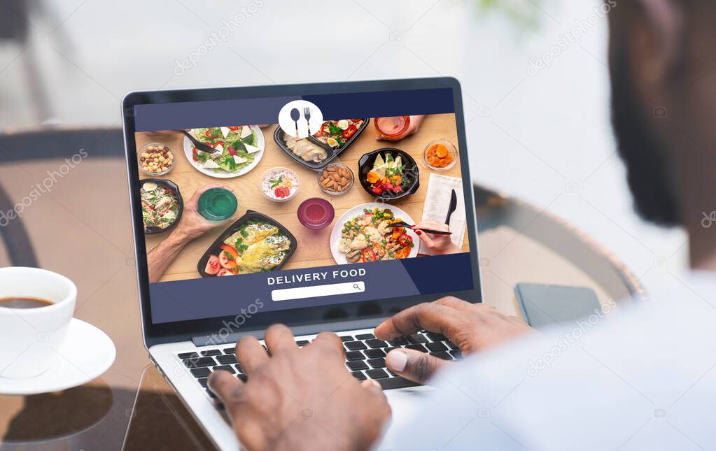 Modern food and fast delivery at home or office. African american man uses laptop and order meal