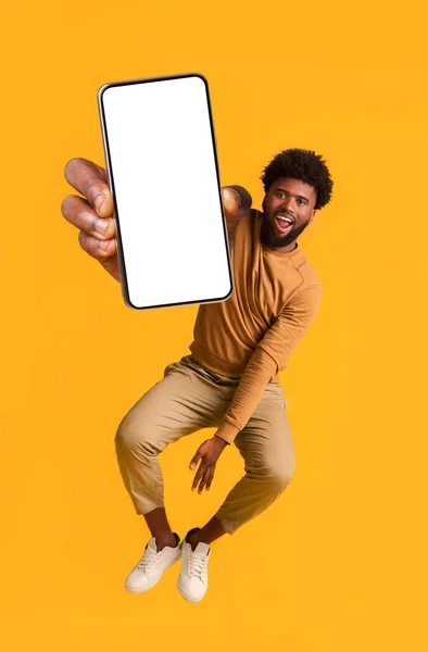 Excited black guy holding smartphone, jumping up — Stock Photo, Image