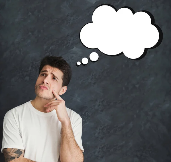 Broody millennial man with blank thought cloud over grey background, mockup for design