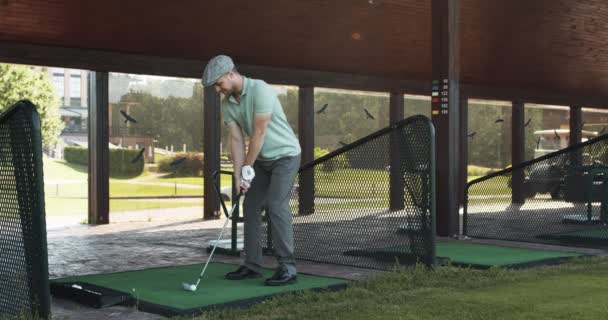 Joven jugando al golf en el club, golpeando la pelota en el curso de entrenamiento individual — Vídeos de Stock