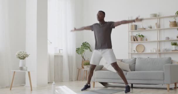 Młody, aktywny, afrykański mężczyzna robi ćwiczenia skokowe w domu, intensywny trening wytrzymałościowy — Wideo stockowe