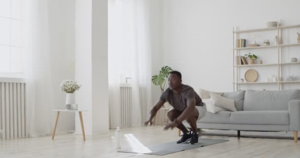 Mladý africký Američan cvičit burpee cvičení doma, dělat kliky a skákání, zpomalený film — Stock video