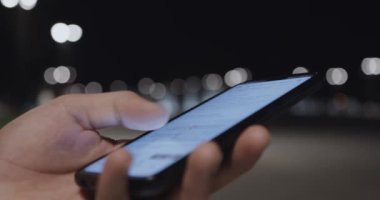 Modern akıllı telefonun erkek ellerinde yakın plan görüntüsü, adam sosyal medya ile cihaz ekranını kaydırıyor