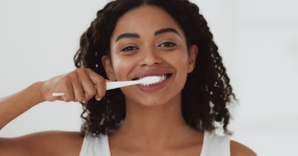 Портрет молодой веселой африканской женщины, чистящей зубы, замедленной съемки — стоковое видео