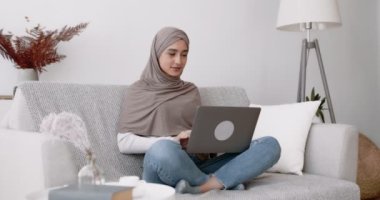 İnternette harika haberler var. Neşeli Arap kadın dizüstü bilgisayara bakıyor çığlık atıyor ve heyecanla el kaldırıyor.