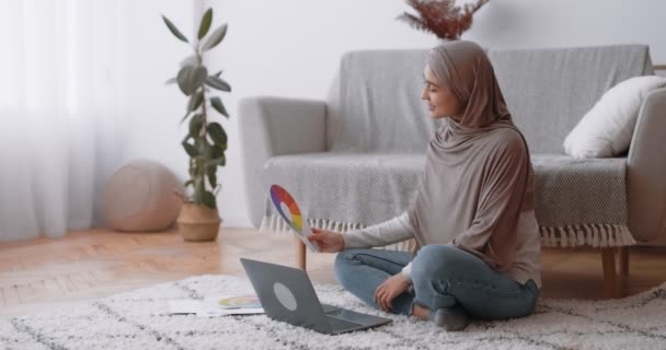 Cursos de design gráfico online. Mulher árabe jovem no hijab segurando paleta gama de cores e trabalhando no laptop — Vídeo de Stock