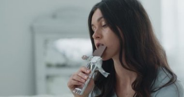 Stres nöbeti. Ağır çekimde çikolata yiyen depresif bir kadının portresi.
