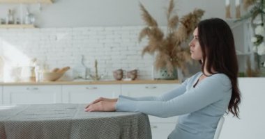 Genç stresli bayan mutfak masasında oturuyor, depresyon ve anksiyeteden muzdarip, yan görüş, ağır çekim