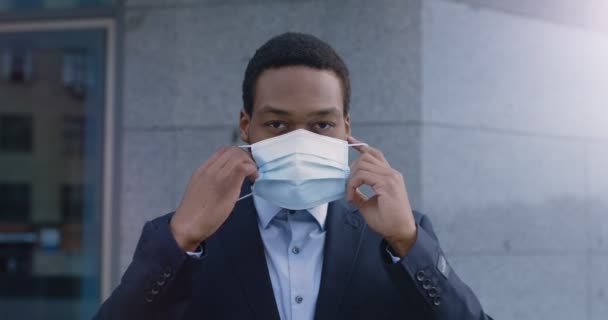 Εξωτερική πορτρέτο του Αφροαμερικανού επιχειρηματία που φοράει προστατευτική ιατρική μάσκα, στέκεται κοντά στο κτίριο γραφείων — Αρχείο Βίντεο