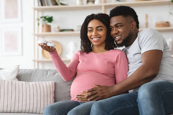 Excited pregnant african american family looking at small baby shoes — Stock Photo, Image