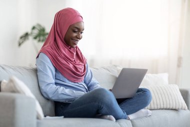 İnternet alışverişi. Siyahi Müslüman Kadın Evde Bilgisayarla Bir şeyler Satın Alıyor