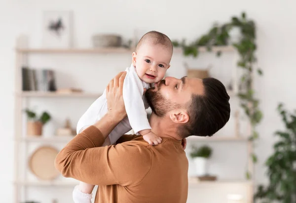 Lindo joven padre besos su pequeño bebé hija en casa —  Fotos de Stock