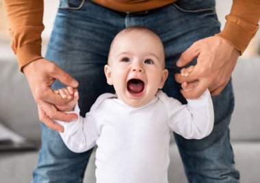 Mutlu küçük bebek yürüyor Babaların elini tutuyor