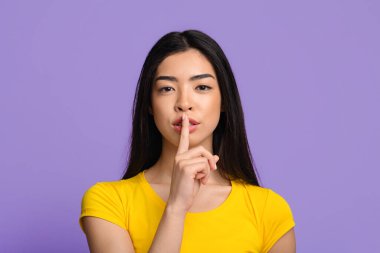 Şşş. Gizemli genç Asyalı bayan kameraya sessizlik işareti gösteriyor.