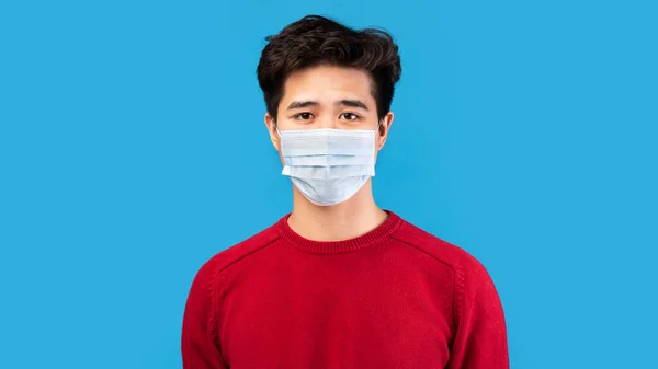 Asiatique guy dans médical masque isolé sur bleu studio mur — Photo