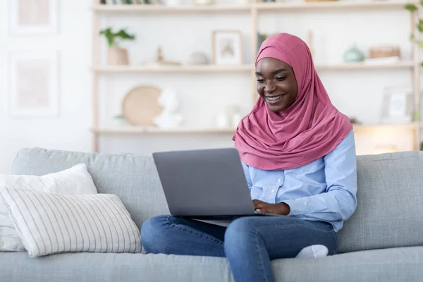 Uzaktan kumanda. Gülümseyen Afrikalı Müslüman Kadın Evde Dizüstü bilgisayar kullanıyor — Stok fotoğraf
