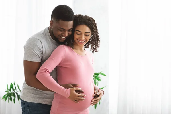 Loving pregnant couple cuddling while spending time at home — Stock Photo, Image