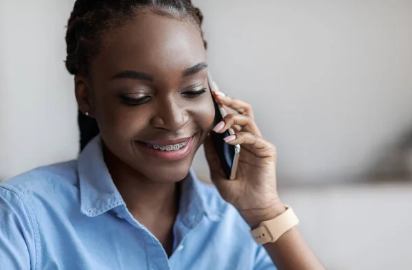 Молодая черная женщина с косичками и зубными брекетами разговаривает по мобильному телефону, крупным планом — стоковое фото