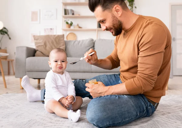 Papá cuchara alimentación bebé durante licencia de paternidad en casa — Foto de Stock