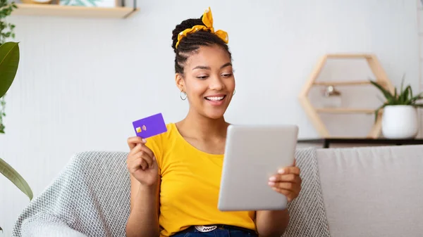 Señora negra sosteniendo la tableta y tarjeta de crédito en casa — Foto de Stock