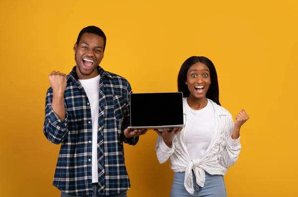 Heureux millénial afro-américain mec et dame exprime des émotions de succès et garder ordinateur portable avec écran vide — Photo