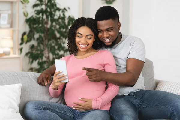 Šťastný těhotný černošky pár pomocí smartphone spolu doma — Stock fotografie