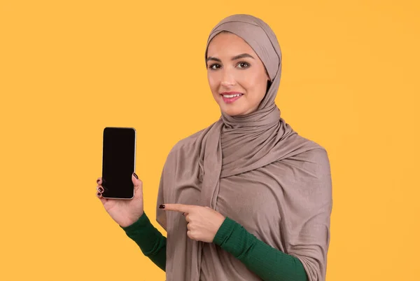 Muslim Lady Menunjuk di Smartphone Screen Posing On Yellow Background — Stok Foto